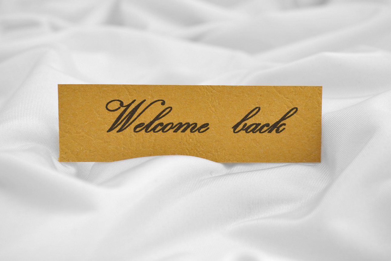 Close up of  Welcome back tag on white satin